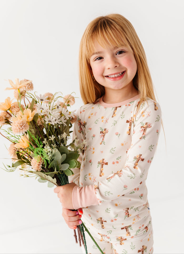 Young girl holding a bouquet of flowers wearing a bamboo pajama set with a floral Easter pattern.