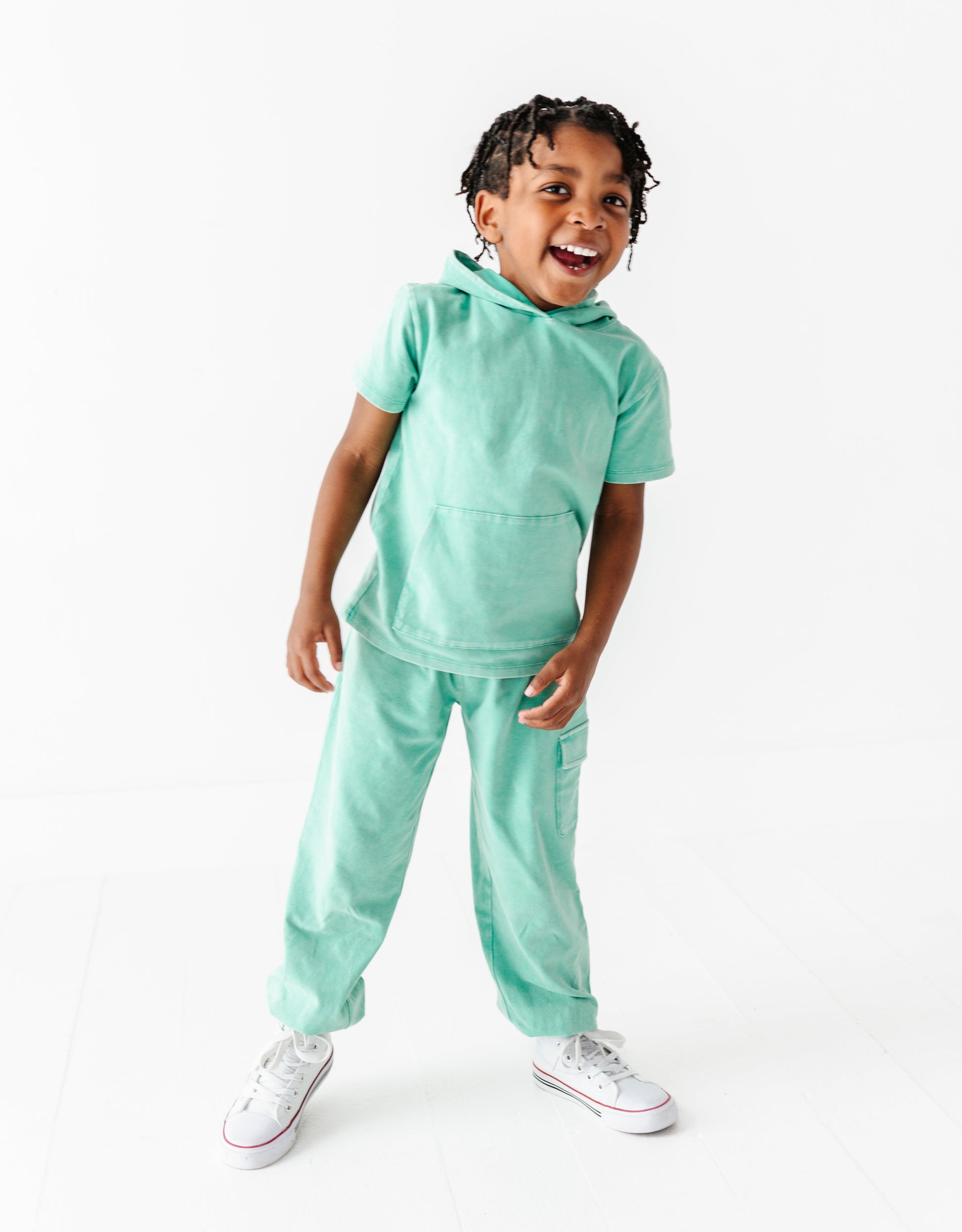 Child wearing a light green outfit on a white background