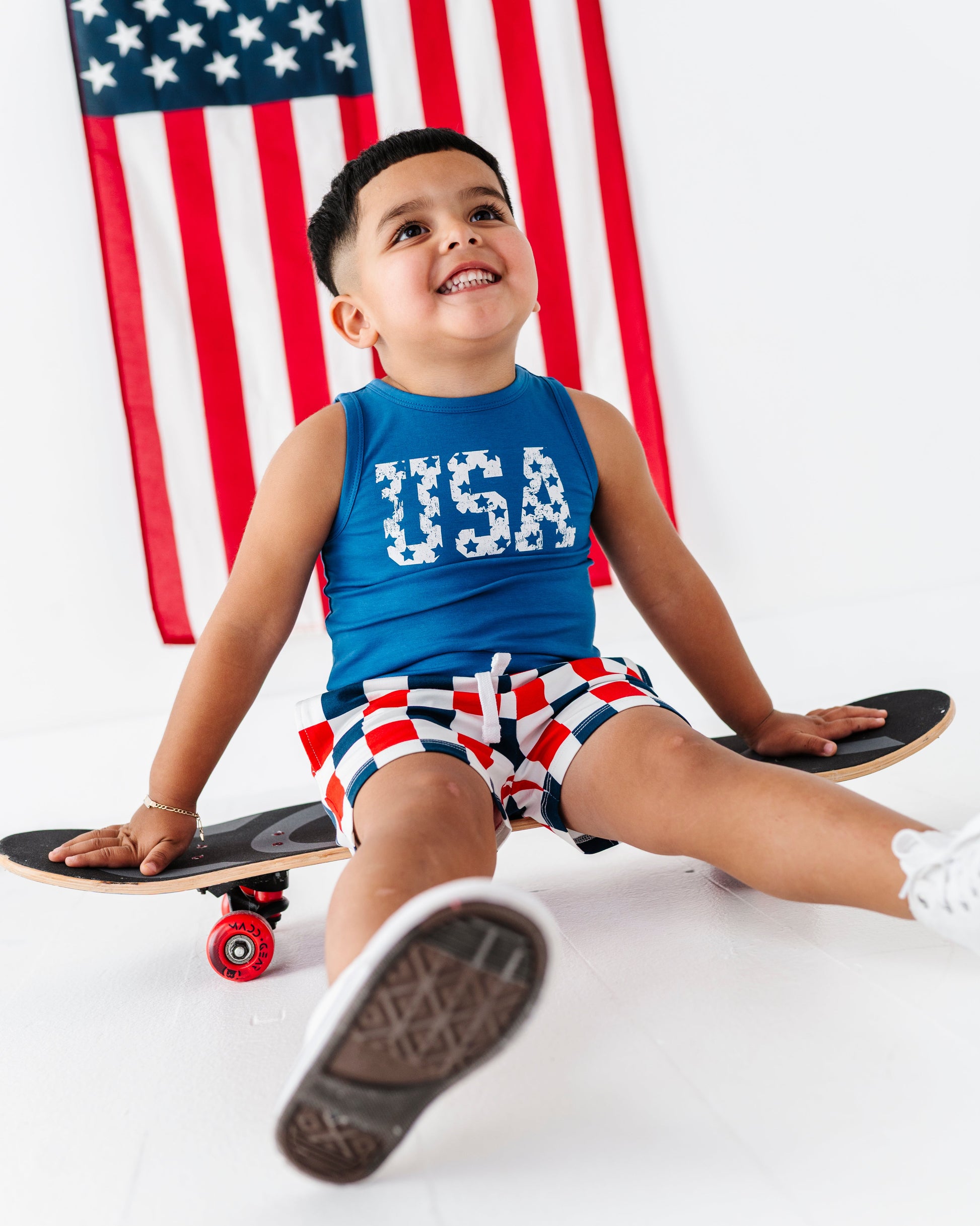 Child sitting on a skateboard with an American flag in the background