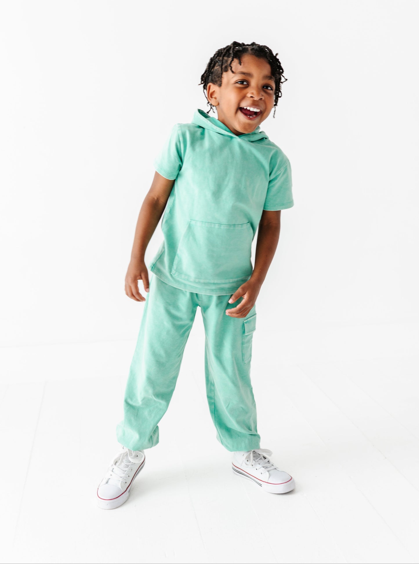 Child wearing a light green outfit on a white background