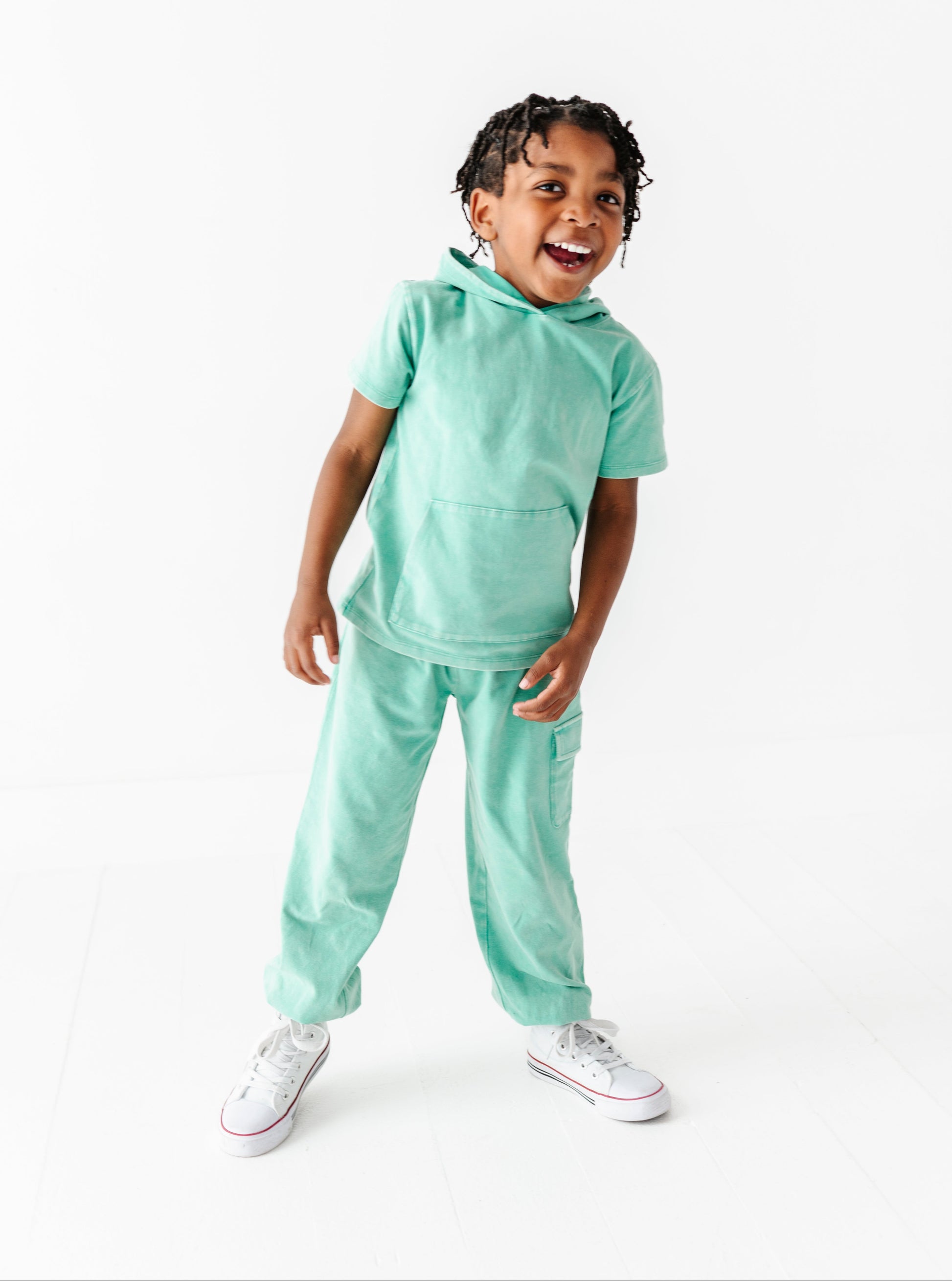 Child wearing a light green outfit on a white background