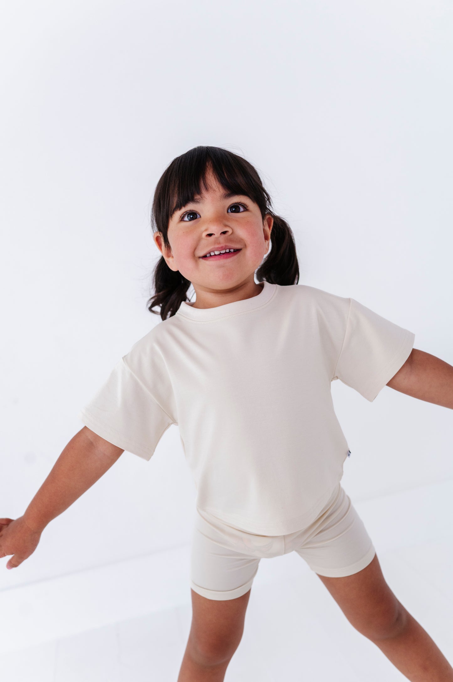 Child wearing an ivory t-shirt and bamboo biker shorts on a white background
