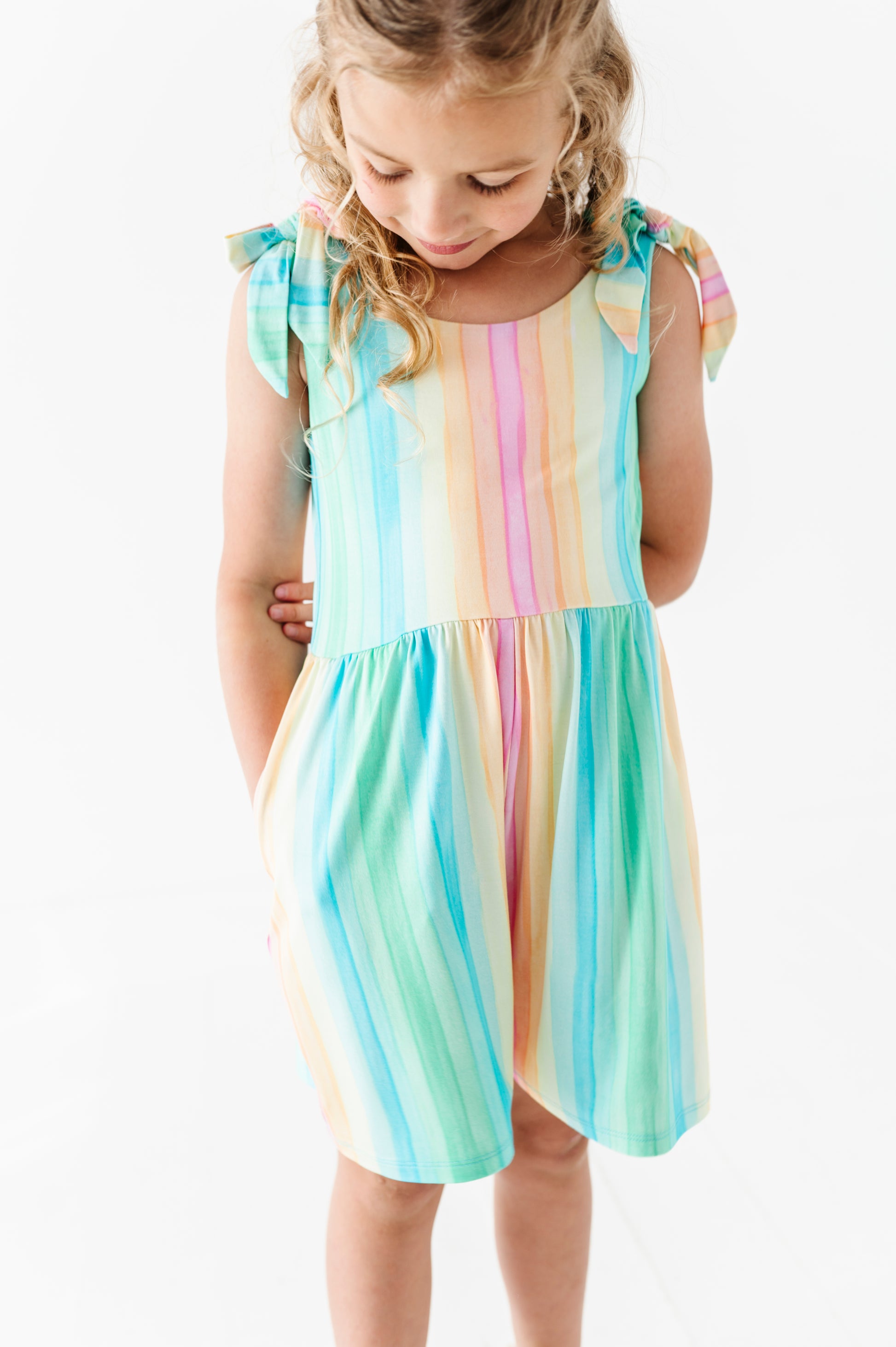 Young girl wearing a colorful striped romper on a white background