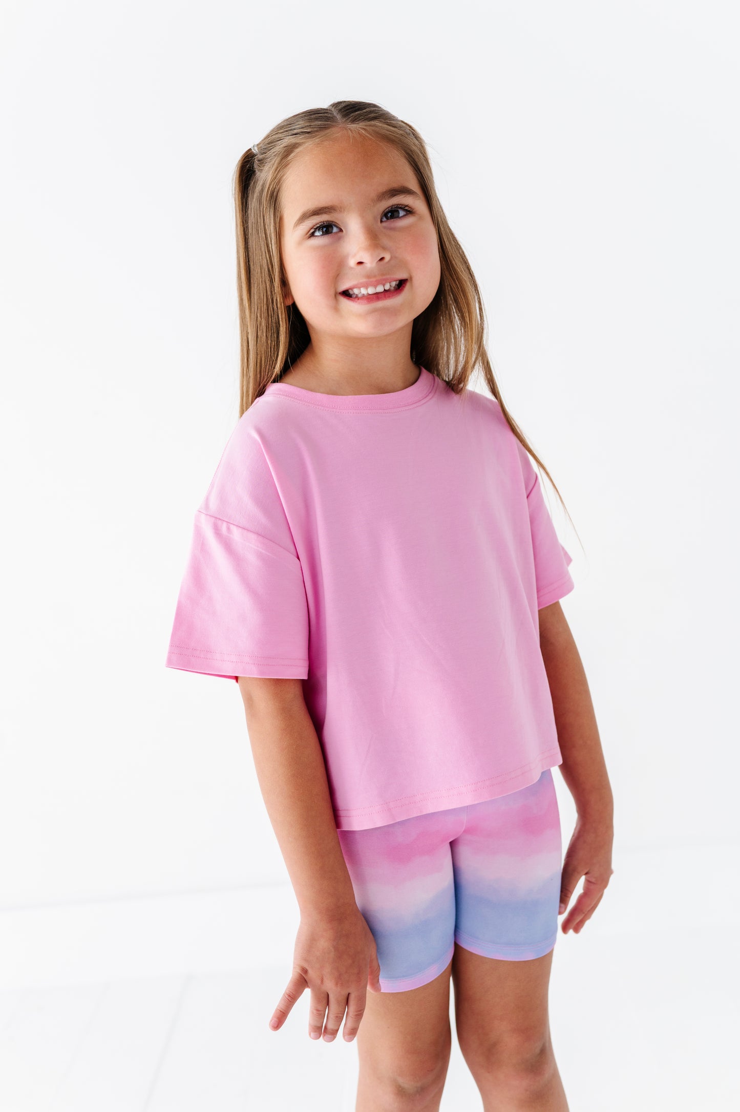 Young girl wearing pink and purple bamboo biker shorts on a white background