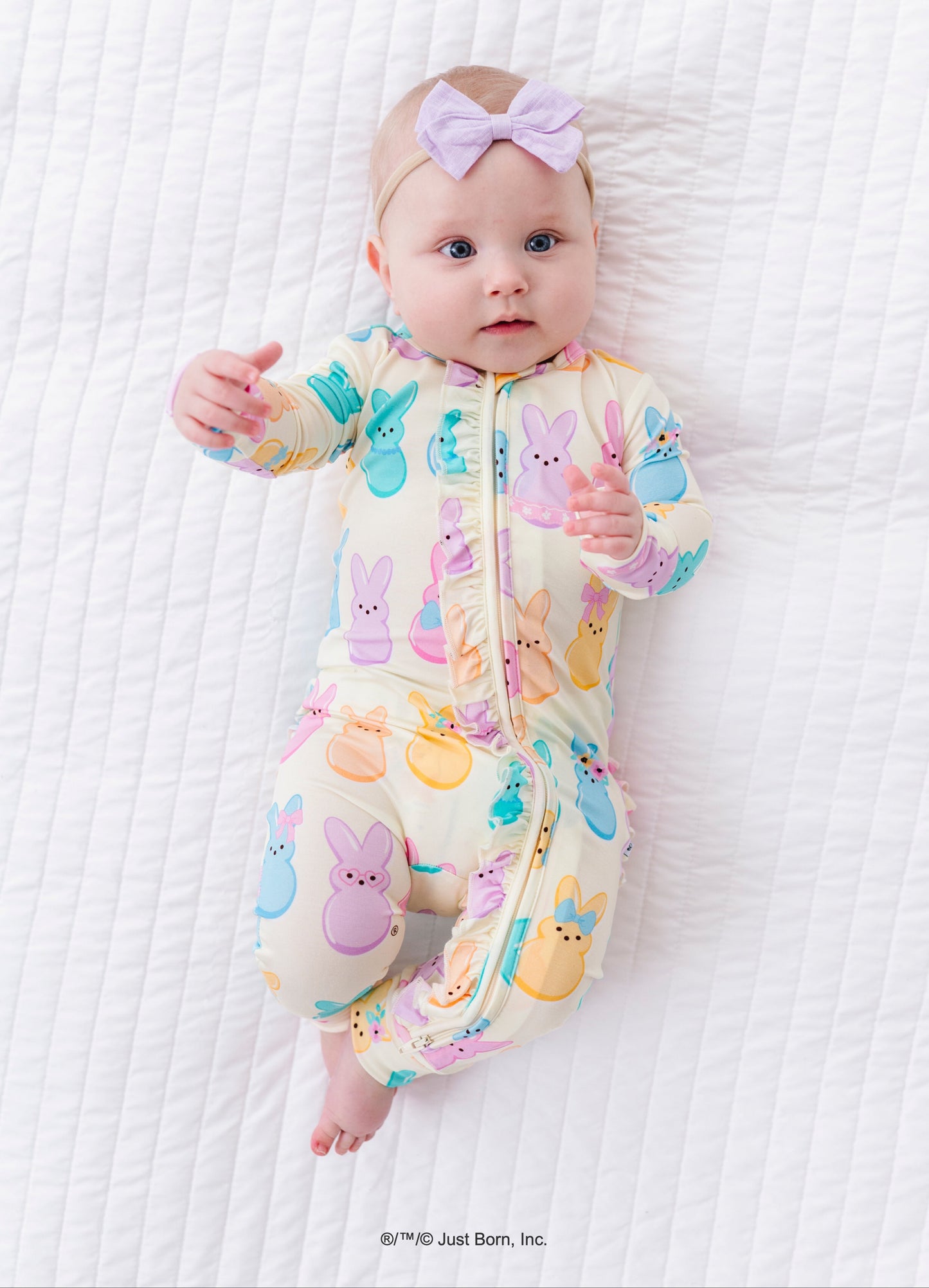 Baby wearing a colorful romper with PEEPS® on a white textured surface