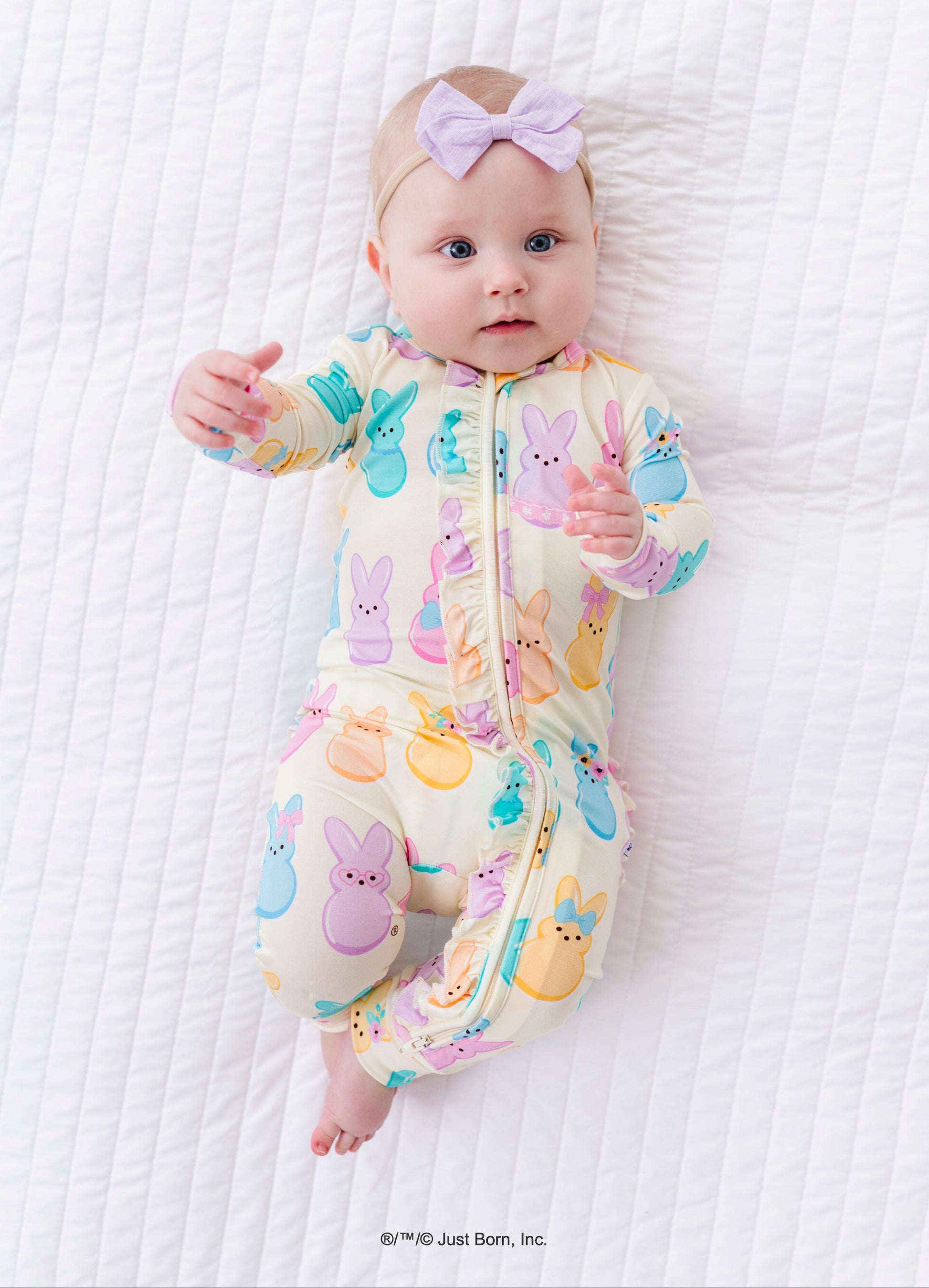 Baby wearing a colorful romper with PEEPS® on a white textured surface