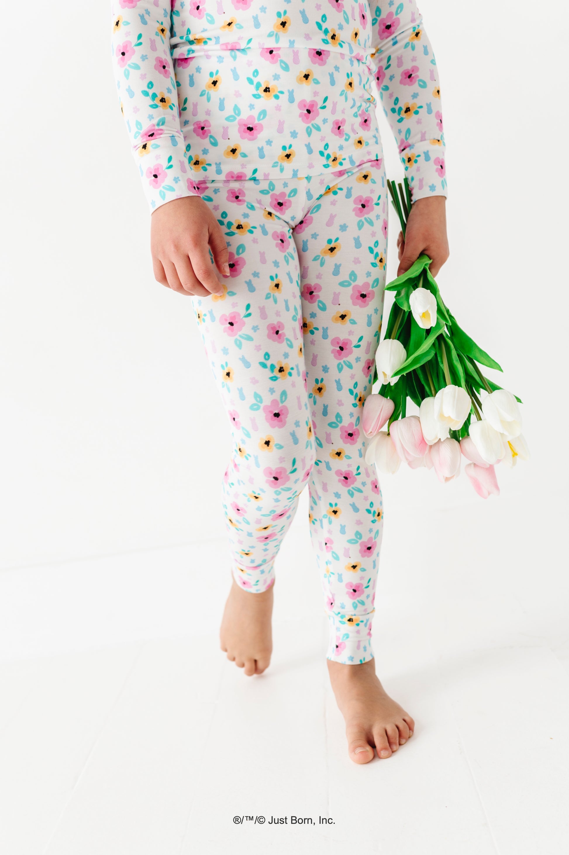 Child wearing a floral PEEPS® pajama set holding tulips on a white background