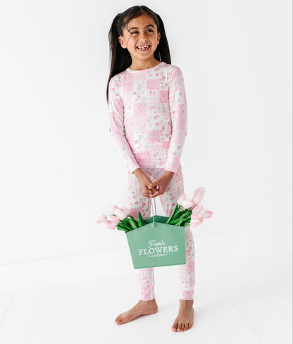 Young girl in pink floral bamboo two-piece pajamas holding a basket of flowers on a white background