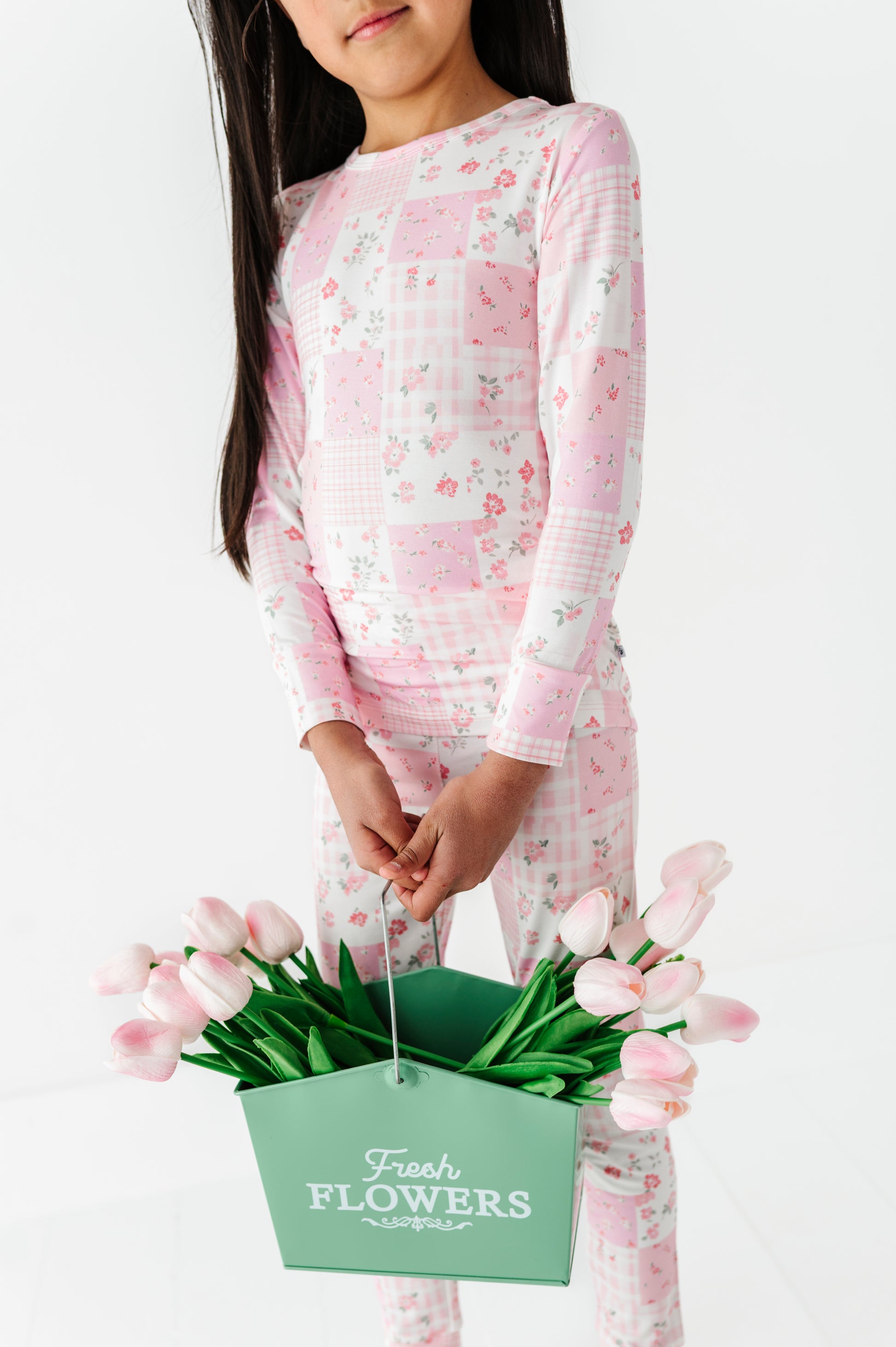 Young girl wearing pink floral bamboo two-piece pajamas and carrying a basket of flowers 