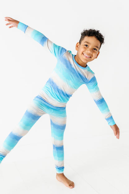 Child wearing a blue and white striped bamboo pajama set on a white background