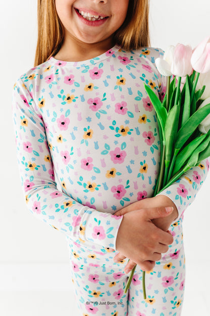 Child wearing a floral-patterned outfit holding tulips against a white background