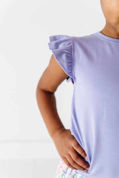 Child wearing a light purple bamboo/cotton top with ruffled sleeves on a white background