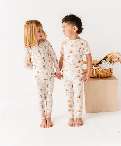 Two children wearing pajamas with a pattern of crosses for Easter, standing on a white background.