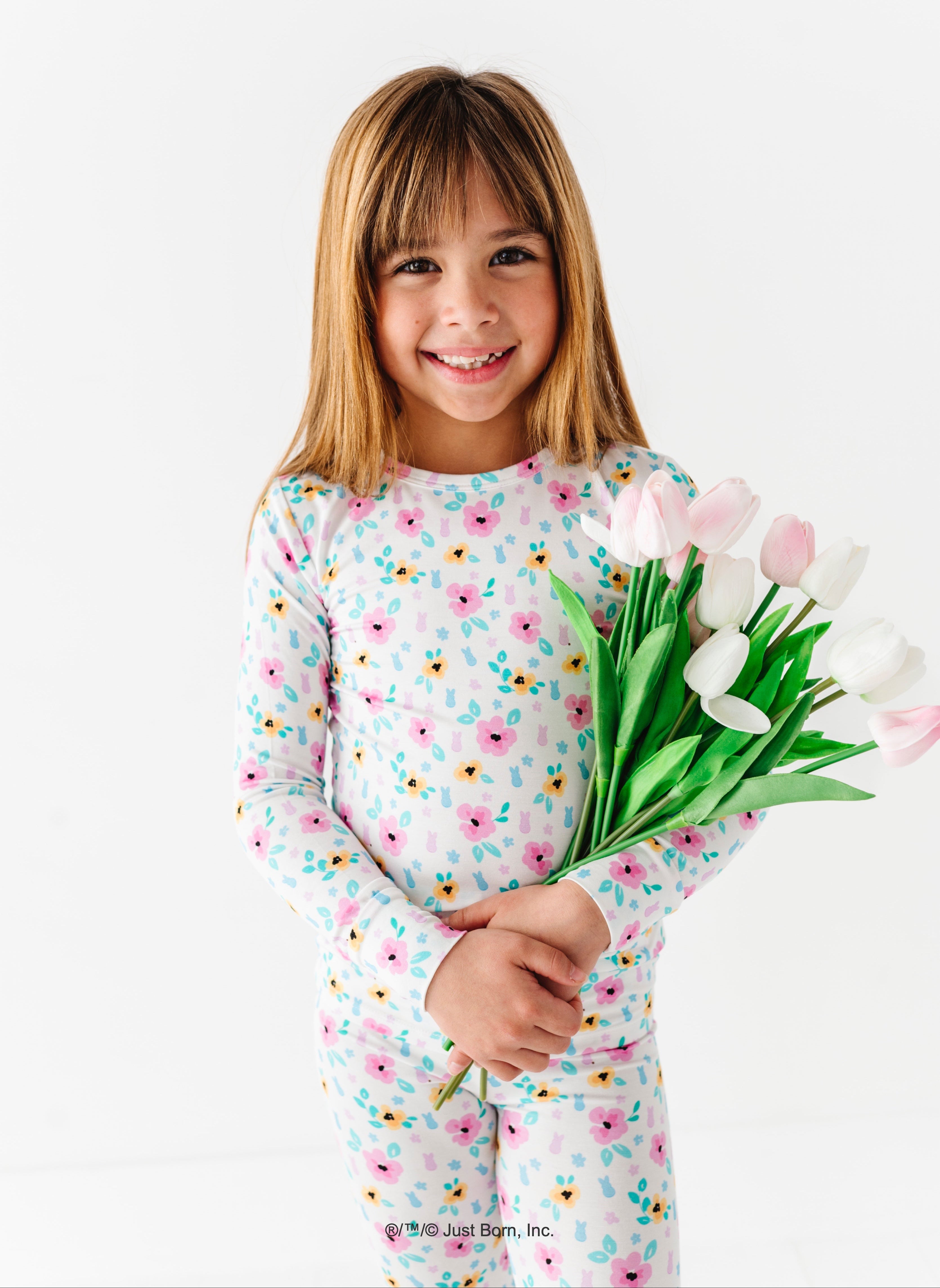 Young girl in a floral PEEPS® pajama set holding tulips on a white background