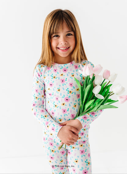 Young girl in a floral PEEPS® pajama set holding tulips on a white background