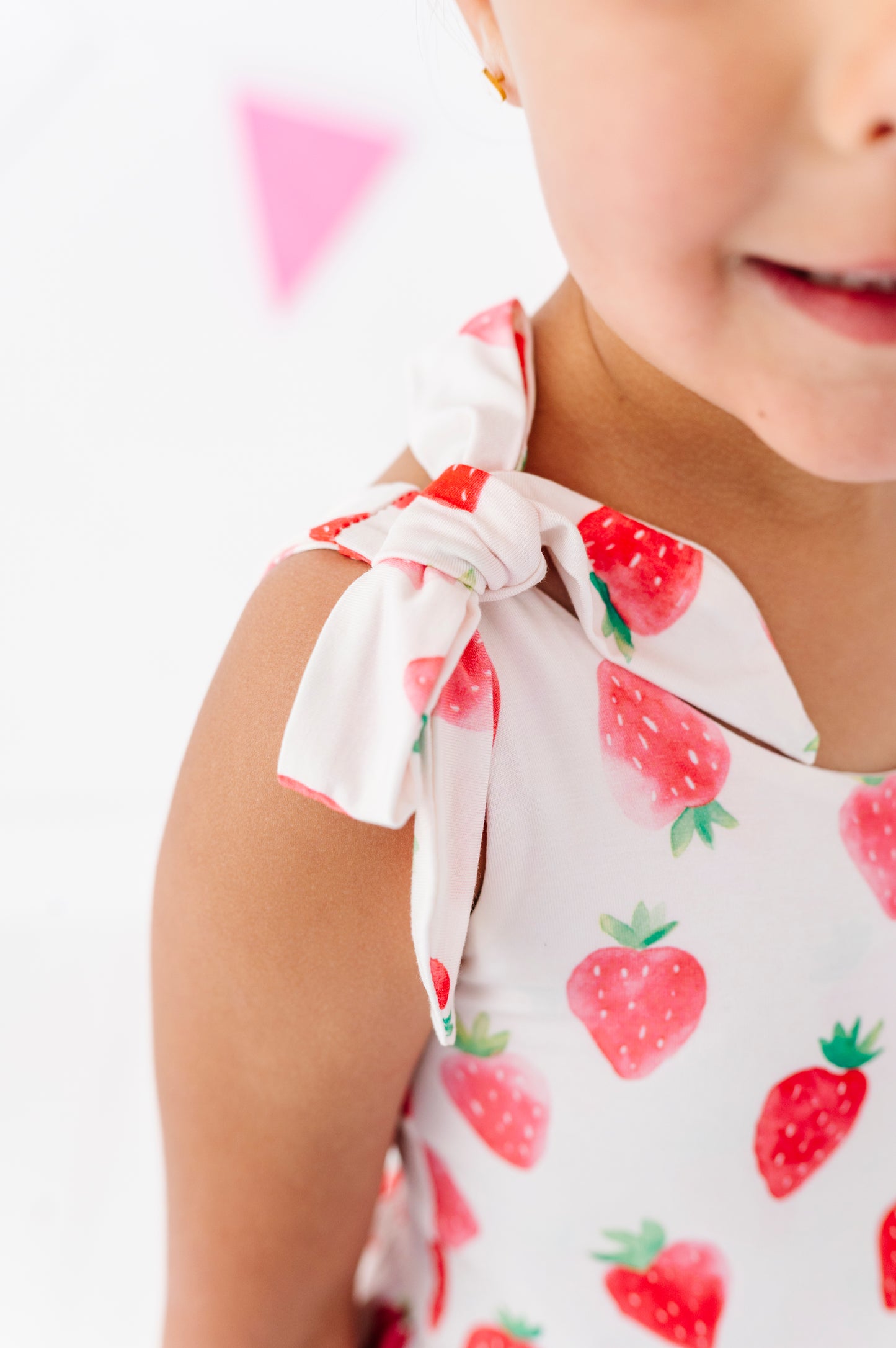 Child wearing a white outfit with red strawberry pattern on a white background