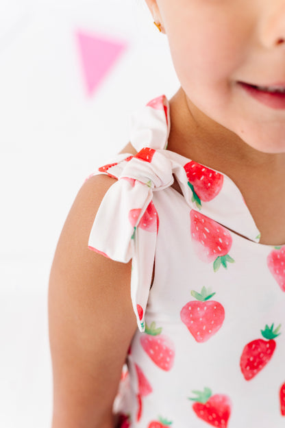 Child wearing a white outfit with red strawberry pattern on a white background