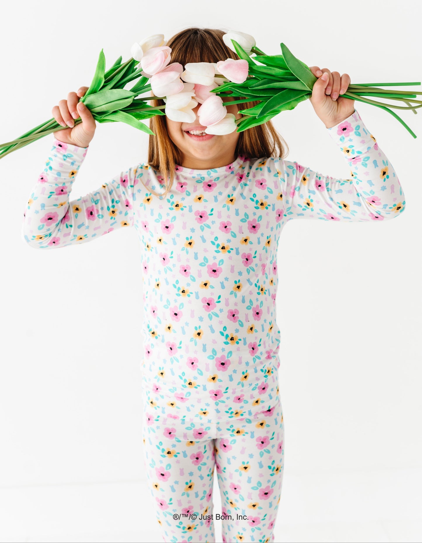 Child wearing a floral PEEPS® onesie holding tulips against a white background