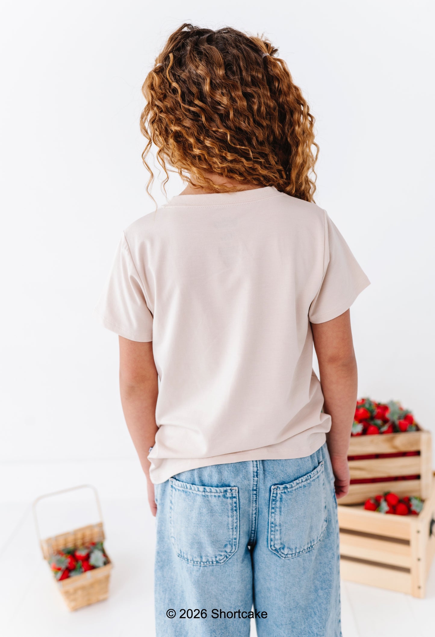 Little girl wearing a beige Strawberry Shortcake™ tee 