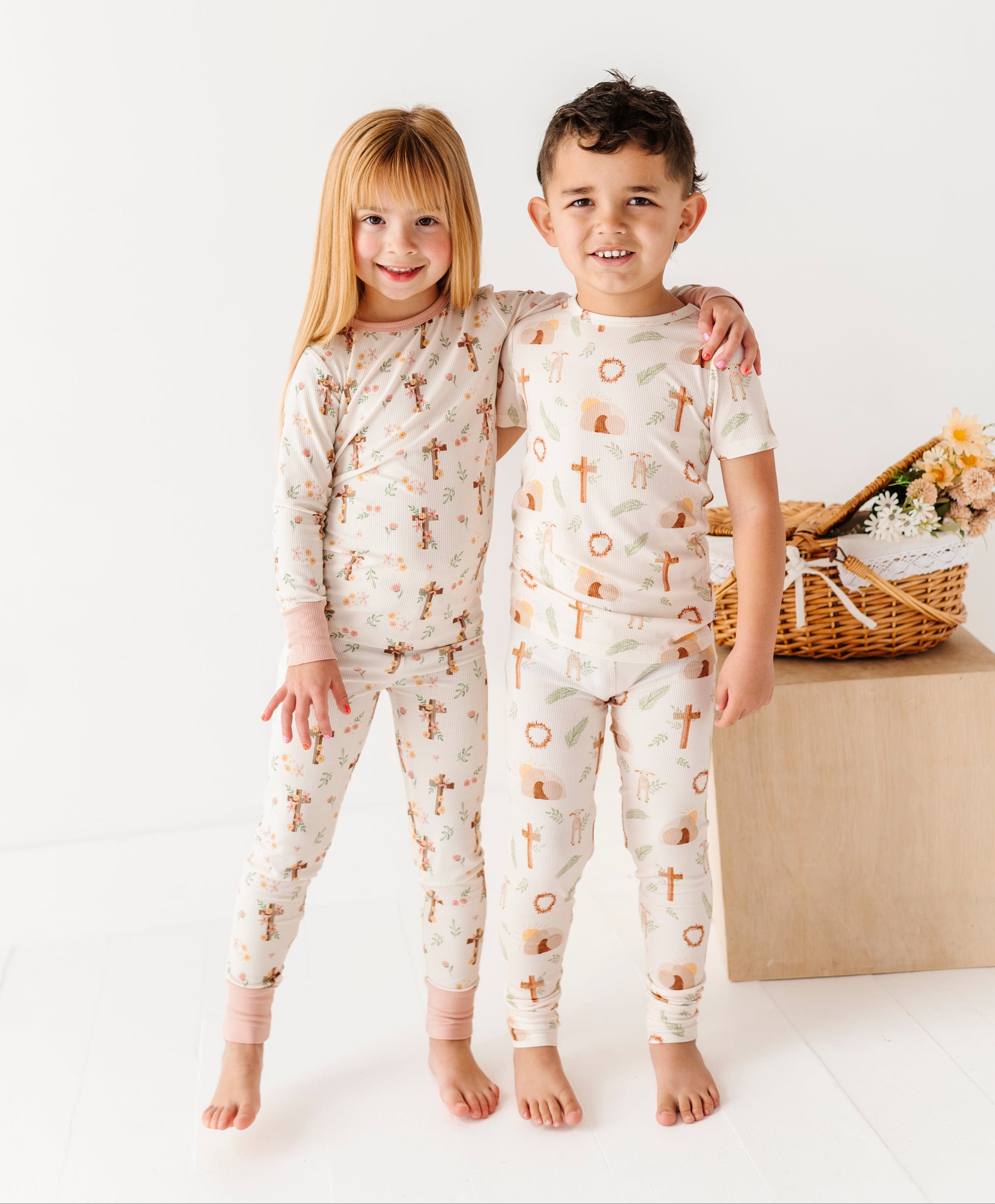 Two children wearing Easter pajamas with a cross pattern on a white background