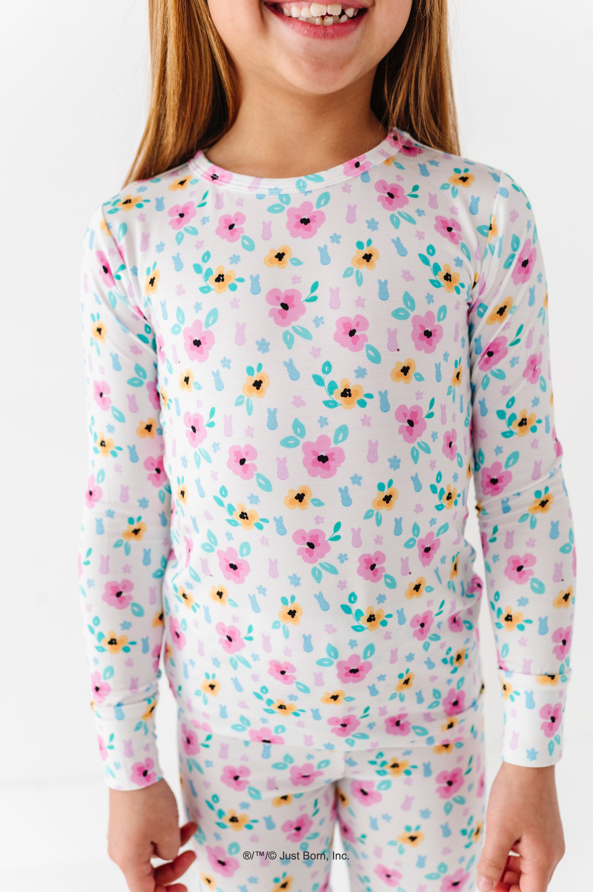 Child wearing floral PEEPS® long-sleeve pajamas on a white background