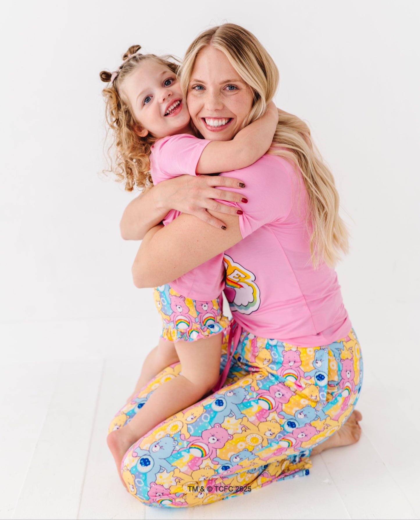 Woman and child wearing pink Care Bears™ “Team Care” pajamas