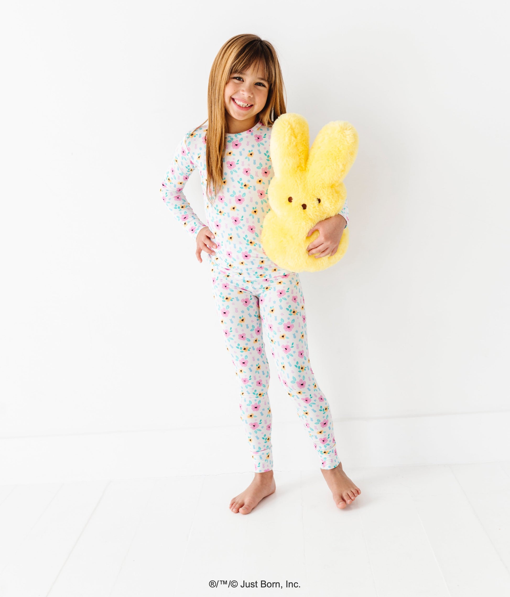 Child wearing a colorful bamboo pajama set holding a yellow PEEPS® plush toy against a white background