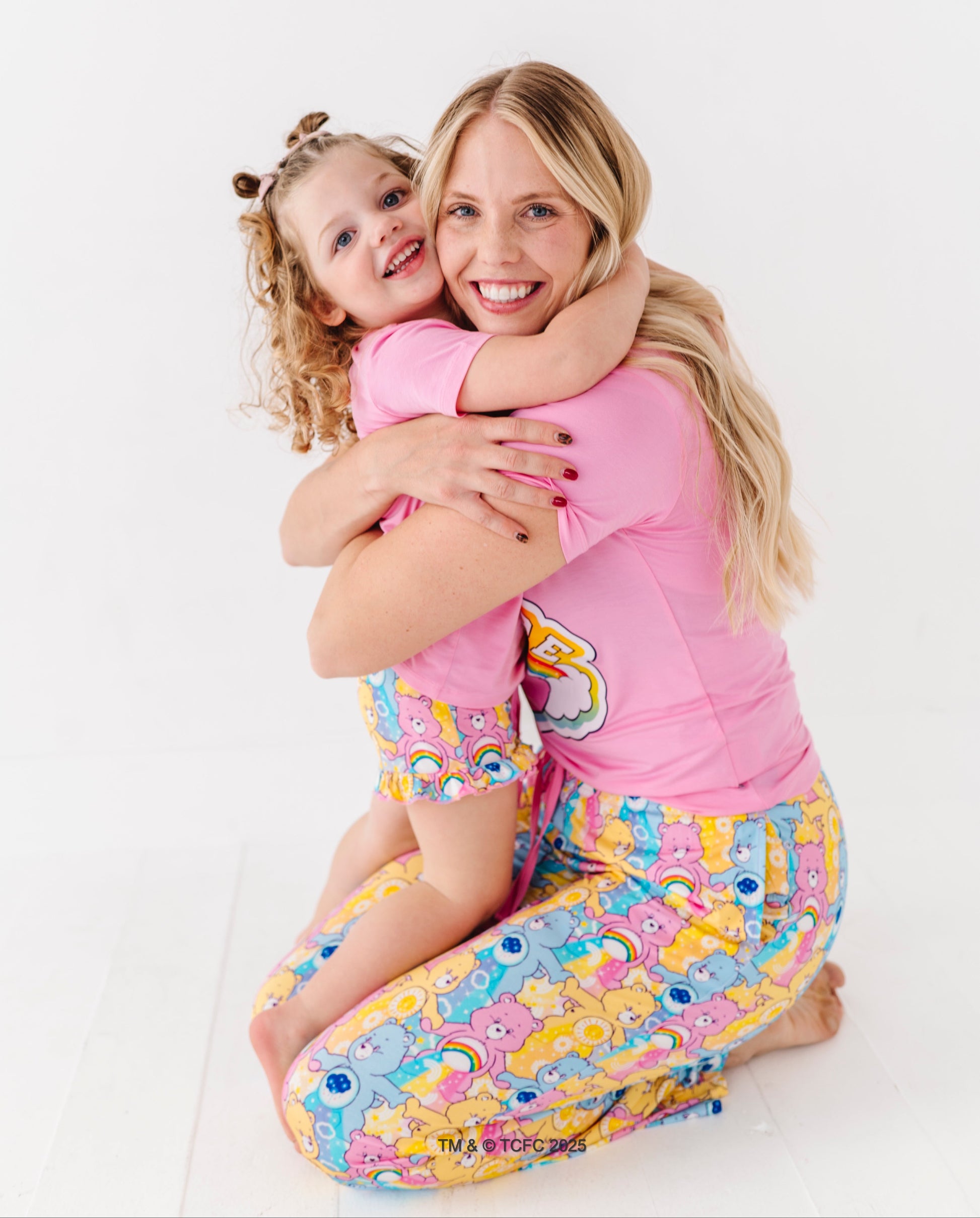 Matching mom and toddler wearing Care Bears bamboo pajama sets on white background
