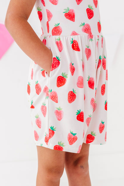 White romper  with red strawberry pattern worn by a young girl