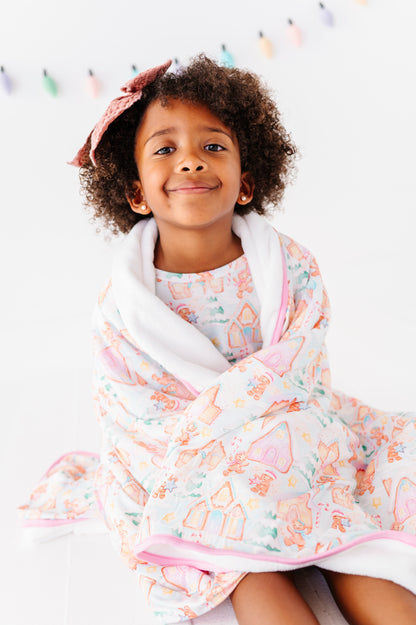 A little girl wrapped in a gingerbread village bamboo plush blanket 