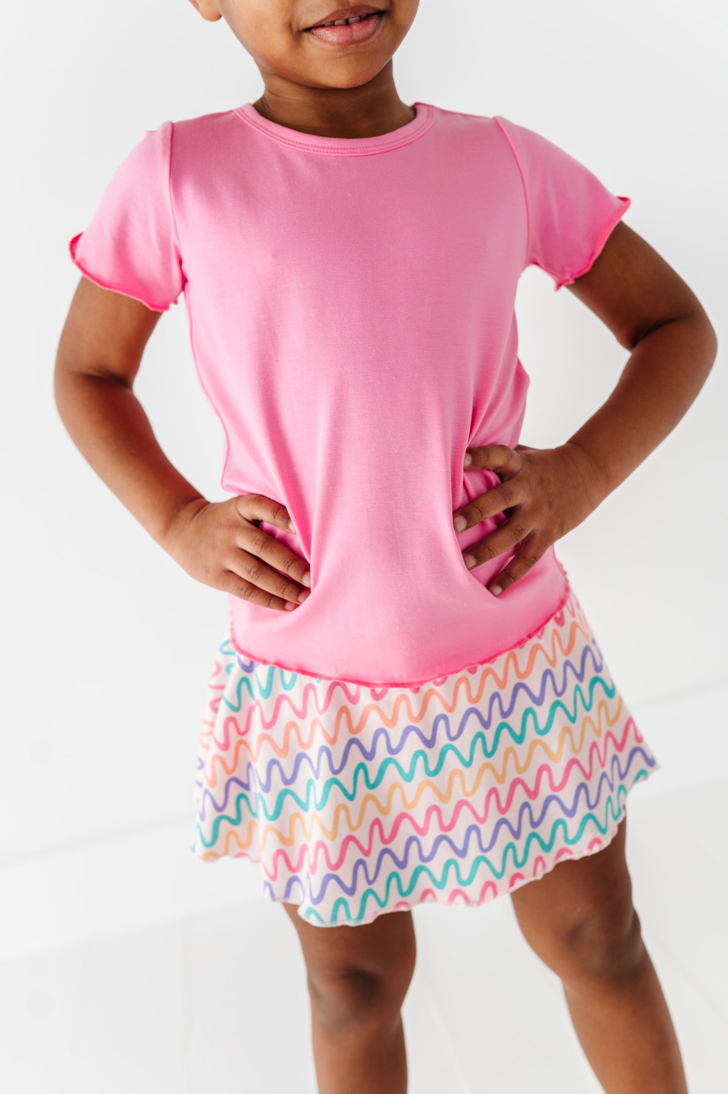 Child wearing a pink bamboo/cotton shirt and colorful bamboo skort on a white background