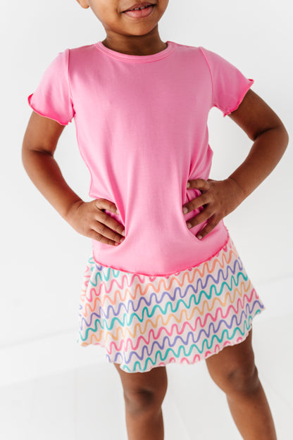 Child wearing a pink bamboo/cotton shirt and colorful bamboo skort on a white background