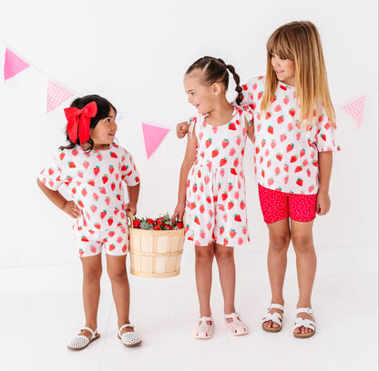 Three children in matching outfits with red strawberries on a white background