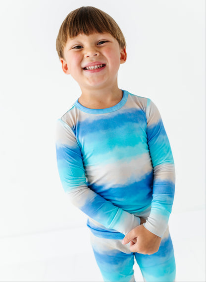 Child wearing a blue and white tie-dye bamboo pajama set on a white background