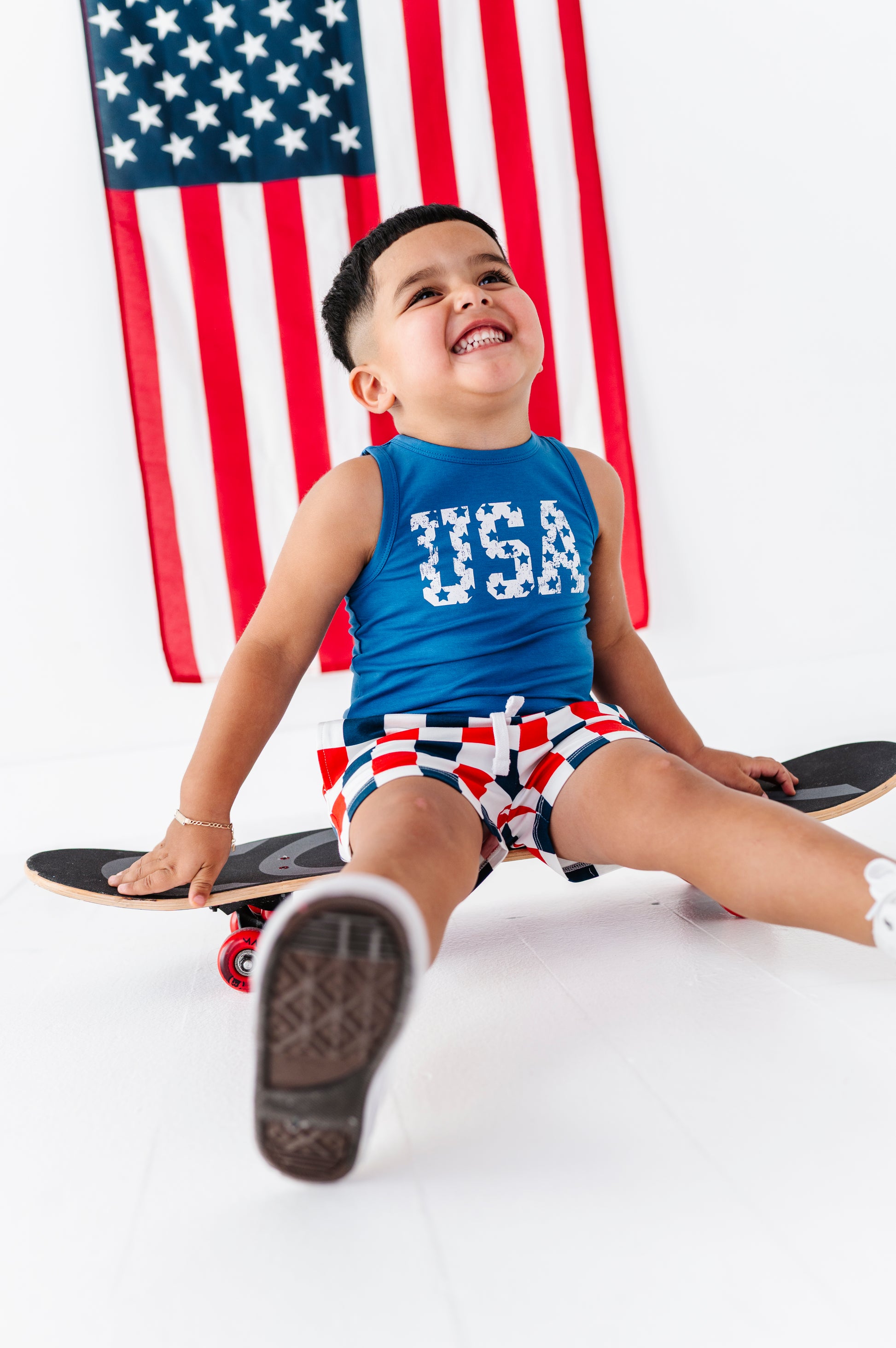 Child sitting on a skateboard with an American flag in the background