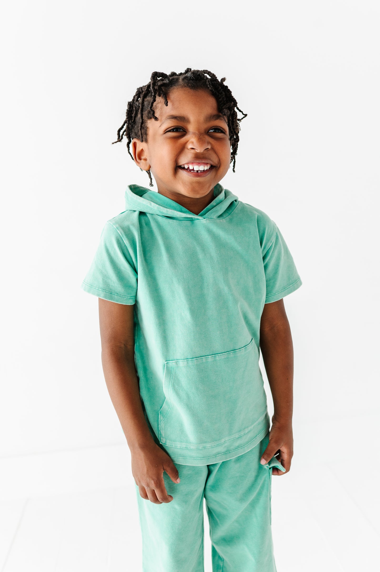 Child wearing a light green hoodie and pants on a white background