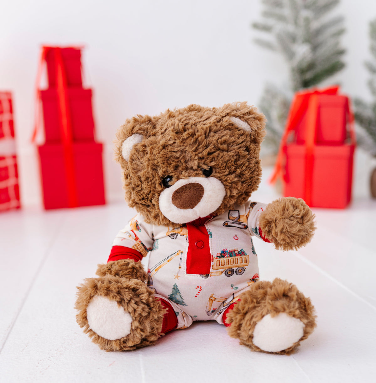 A small teddy bear wearing a holiday construction-themed bamboo romper. 