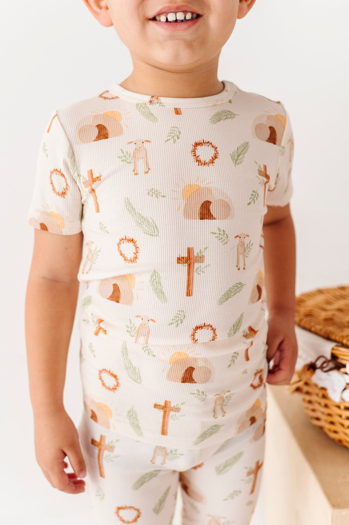 Child wearing a pajama set with Easter-themed crosses print on a light background