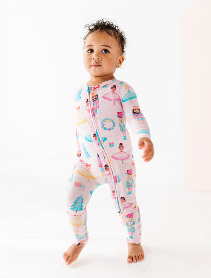 Baby wearing a light pink bamboo onesie with ballerina design on a white background