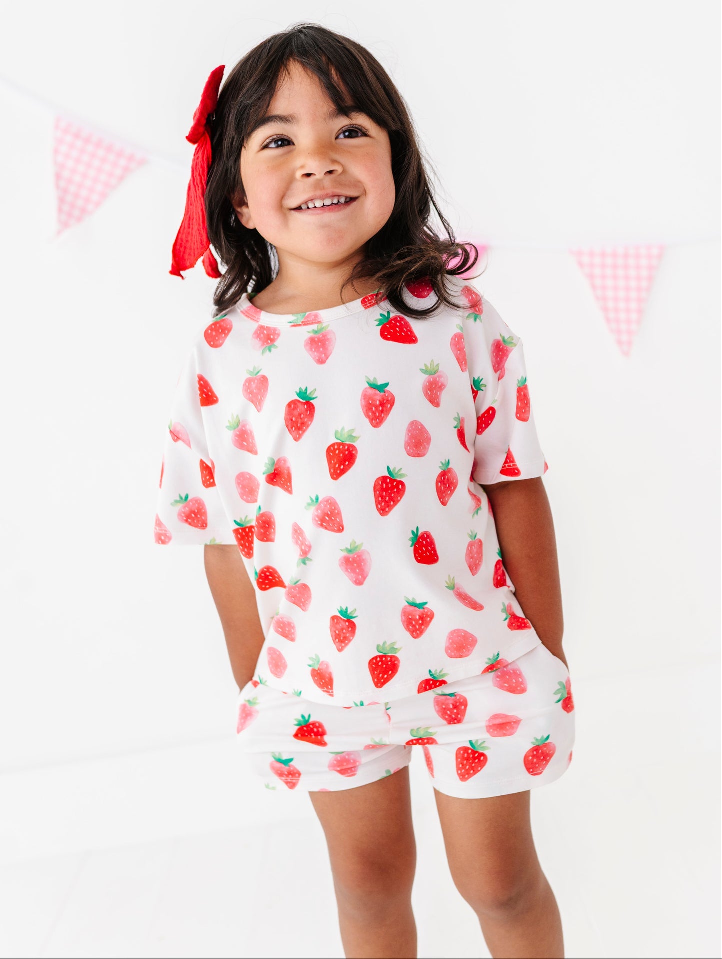 Child wearing a strawberry print outfit on a white background