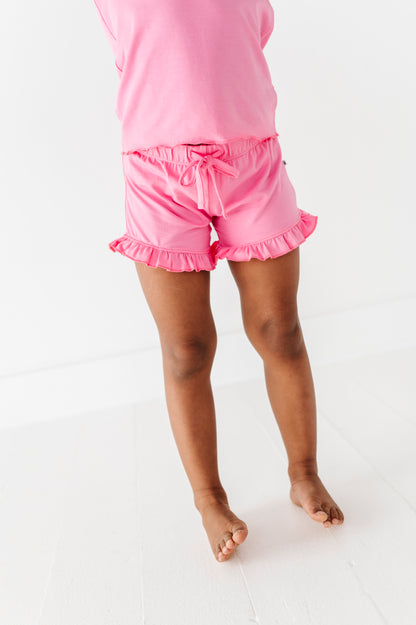 Girl wearing pink bamboo/cotton shorts and top on a white background