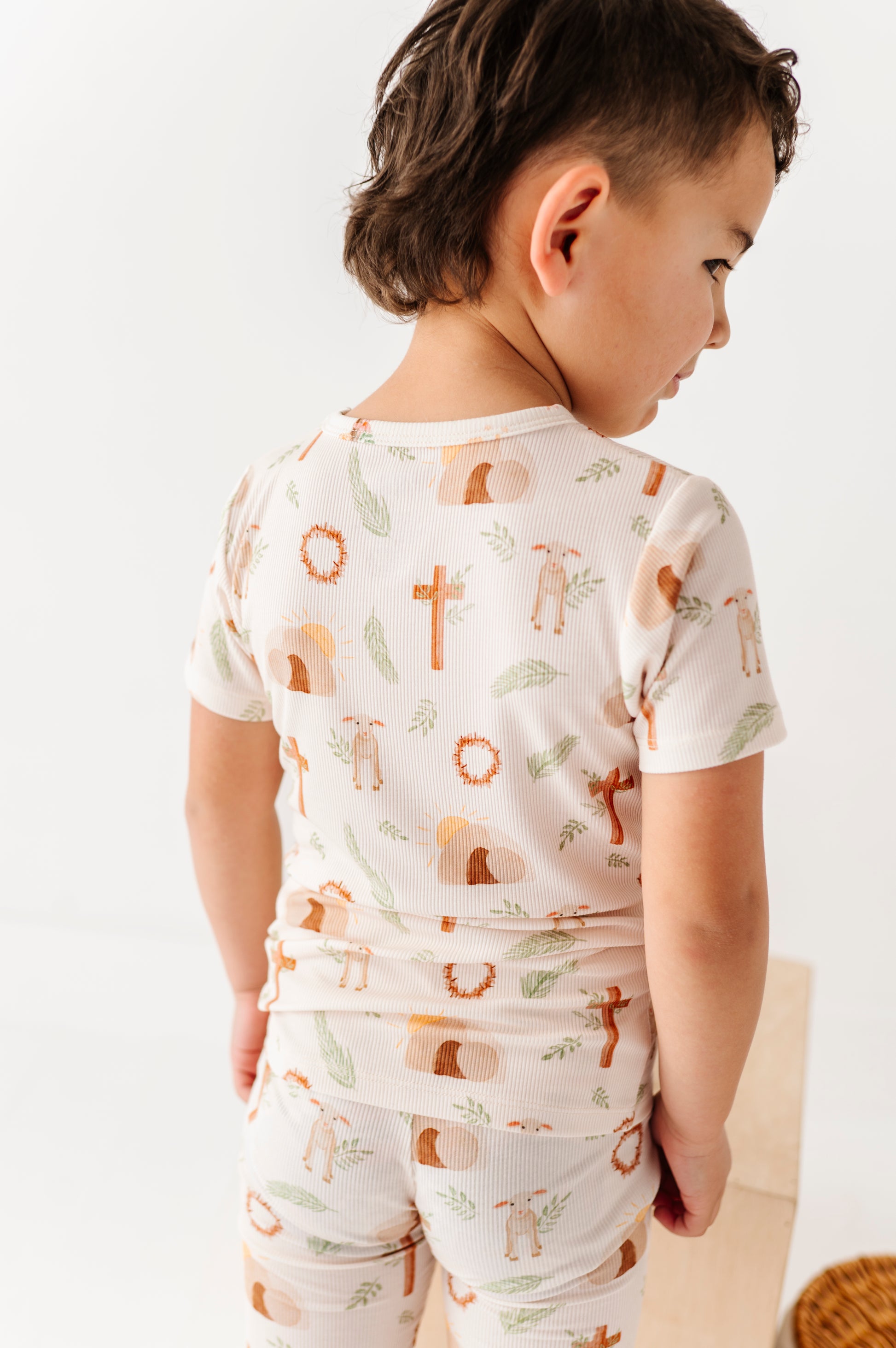 Child wearing a white pajama set with cross print on a light background