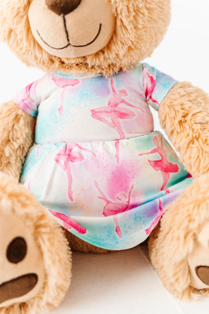 Teddy bear wearing a colorful ballet-themed dress on a light background