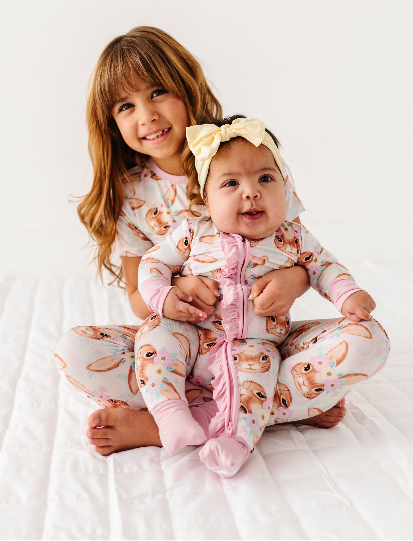 Two children wearing matching bamboo pajamas with animal print on a white background