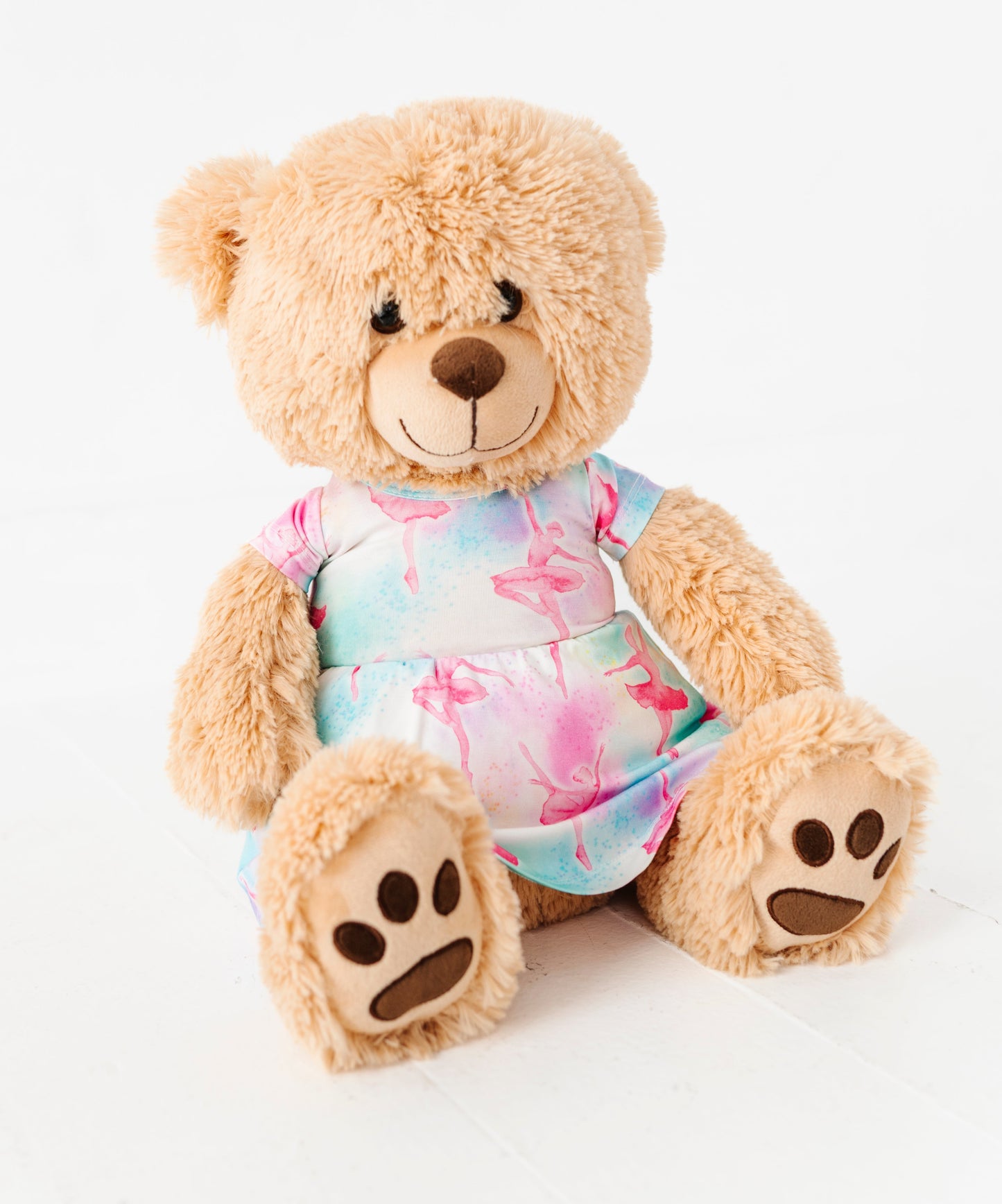 Plush teddy bear wearing a colorful ballet-patterned bamboo dress on a white background