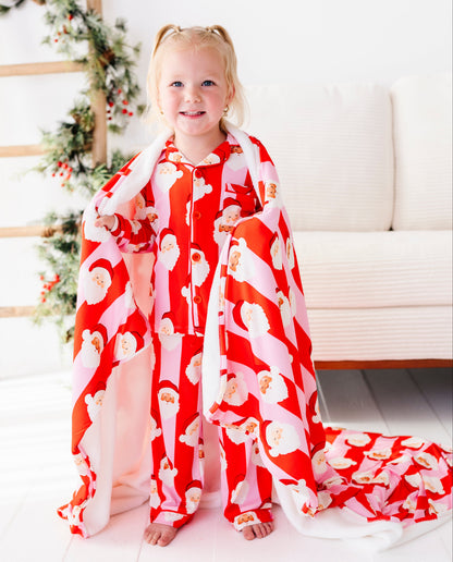 A young blonde girl wearing red-and-pink stripe bamboo pajamas, wrapped in a coordinating red-and-pink stripe bamboo blanket. 