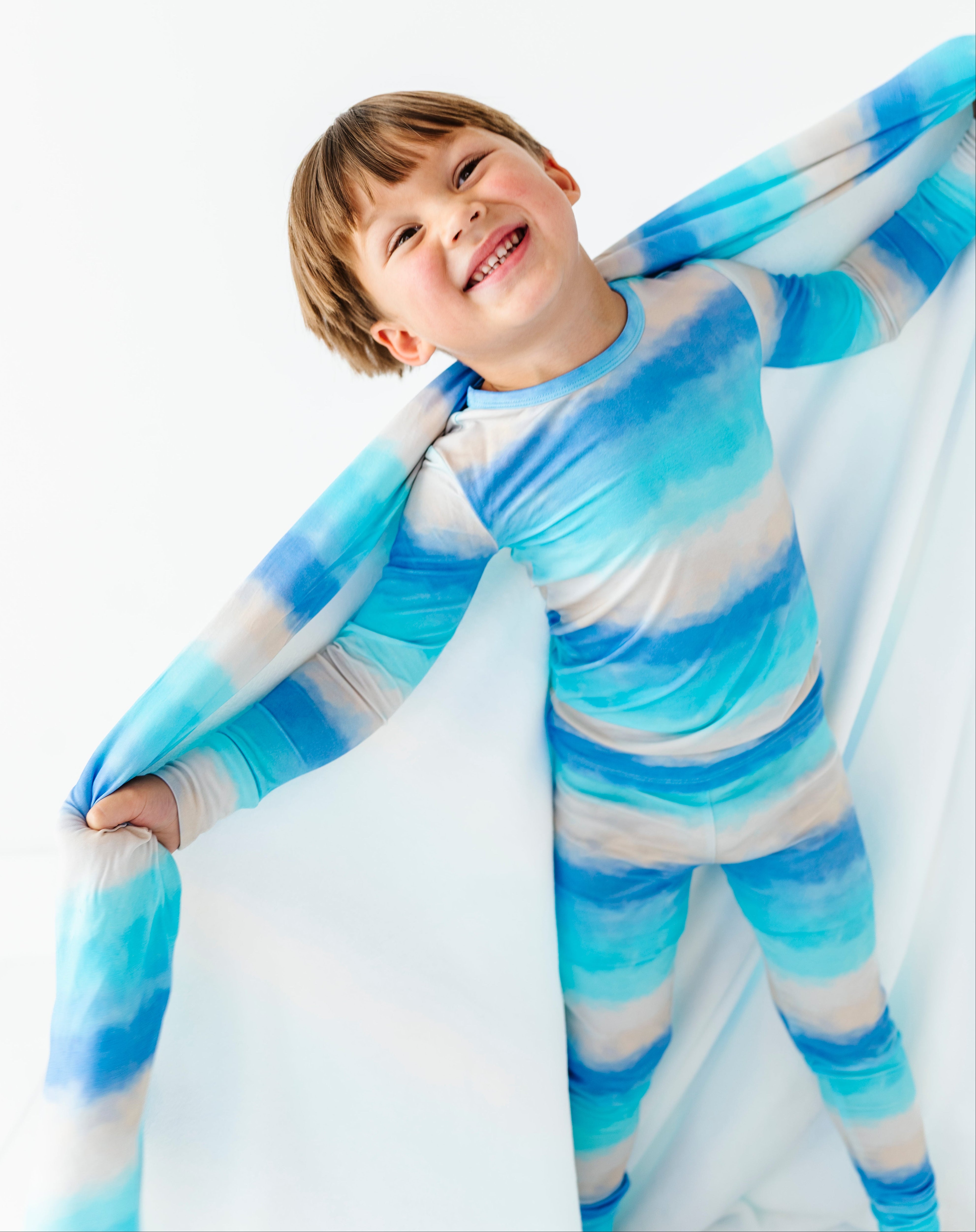 Child wearing a blue and white striped bamboo pajama set with a matching bamboo blanket.