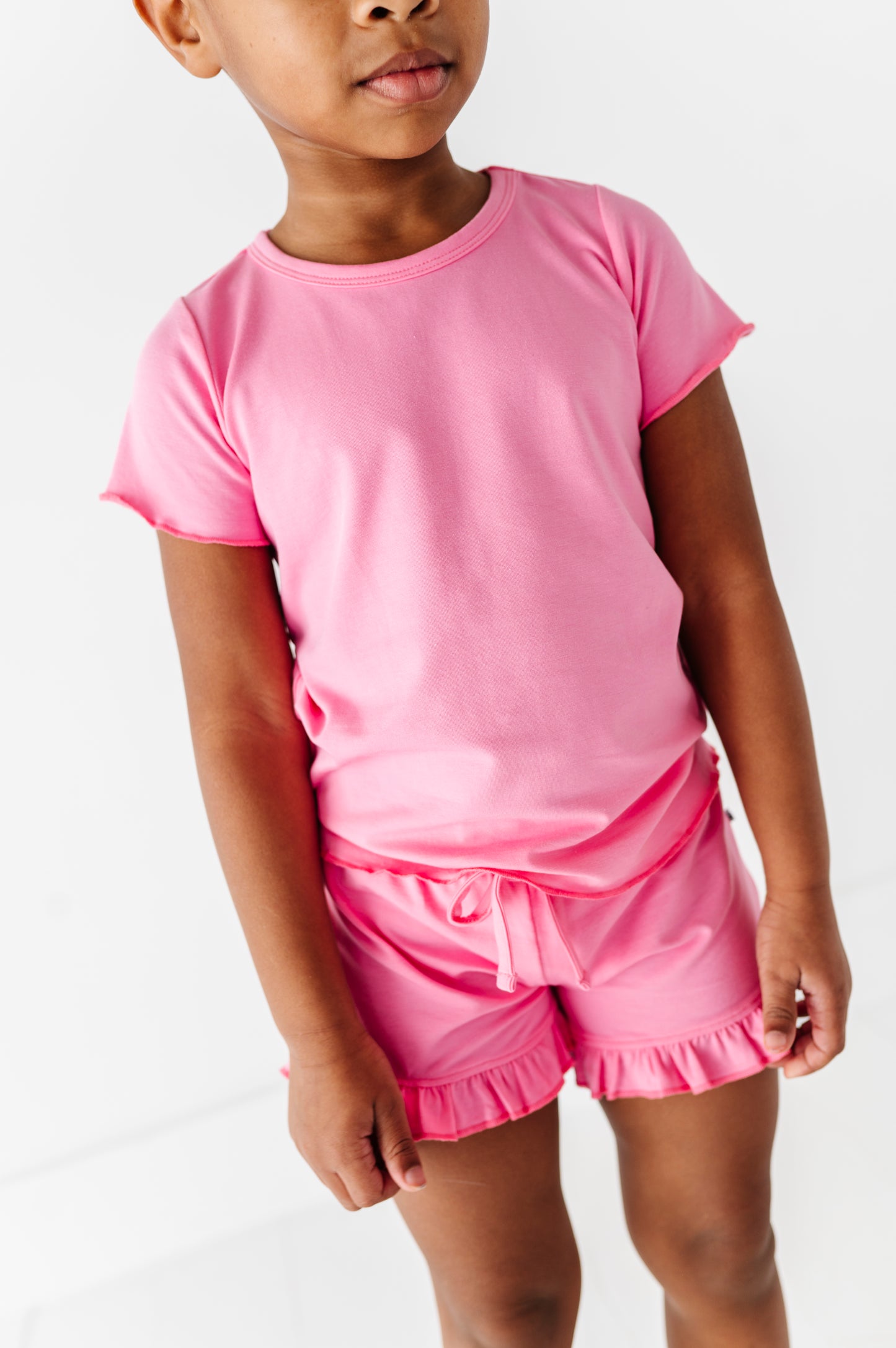 Child wearing a pink bamboo/cotton outfit with a plain background