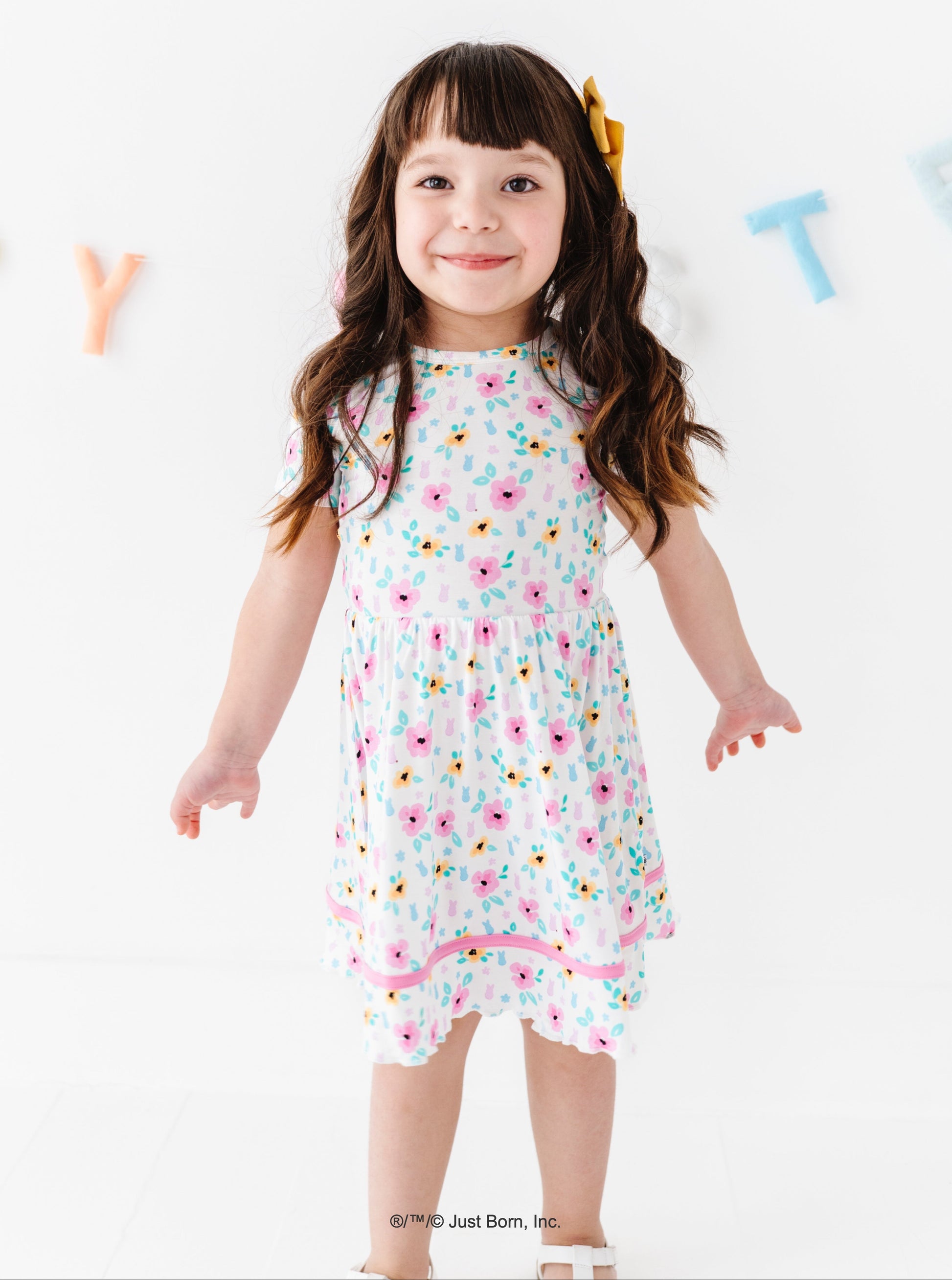 Young girl wearing a floral PEEPS® dress on a white background