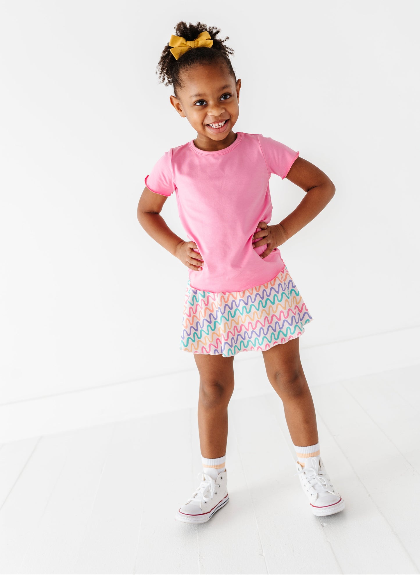 Young girl wearing a pink bamboo/cotton top and colorful bamboo skort on a white background